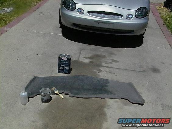 Silver 1999 Ford Taurus front end with cleaning supplies and car mat on driveway