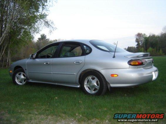 Silver 1999 Ford Taurus sedan parked on grass, rear quarter view
