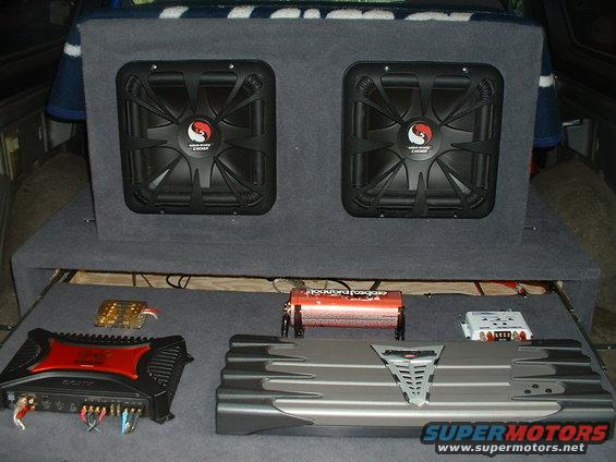 Car interior with two subwoofers in a box and audio amplifiers on a shelf