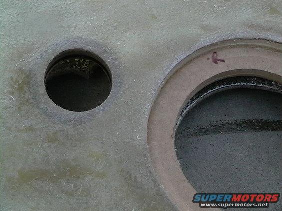 Close-up of two circular openings in a textured surface with a red arrow mark