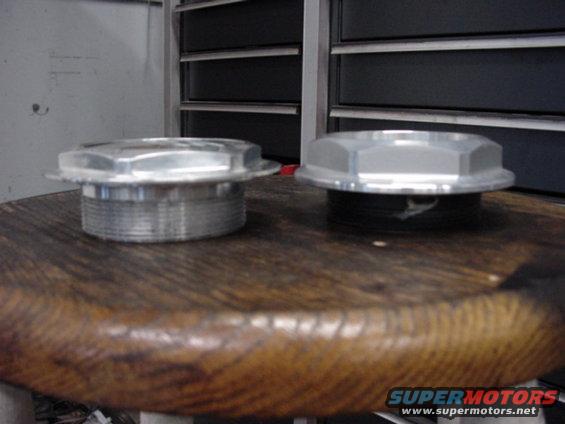 Two silver metal caps with hexagonal tops sit on a wooden surface in front of a metal cabinet