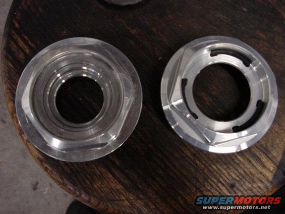 Two machined metal automotive parts on a wooden surface