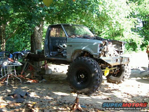 1985 Ford Bronco body on jack stands, missing hood and engine, with large off-road tires
