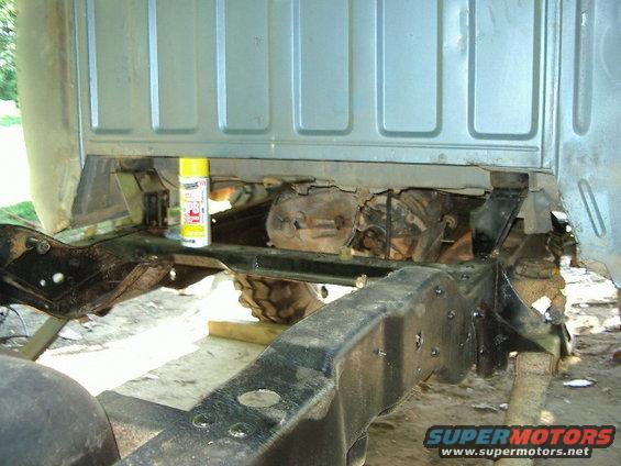 Underneath a truck, showing the frame, transmission, and a can of PB Blaster