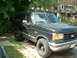 1989 Ford Bronco - A dark-colored 1989 Ford Bronco is parked outdoors, roof-mounted lights and off-road tires.