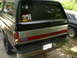 1989 Ford Bronco - The rear of a Ford Bronco shows its taillights, bumper, and a Ford emblem. A license plate and several stickers are visible on the rear.