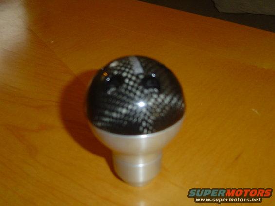 Carbon fiber shift knob with silver base on a wooden surface
