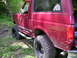 1994 Ford Bronco - Side view of a red 1994 Ford Bronco, modified for off-road use, parked outdoors.