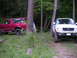 1994 Ford Bronco - Two Ford trucks are parked in a wooded area, with a tent visible behind the Bronco.