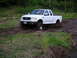 1994 Ford Bronco - White Ford F-150 pickup truck navigates a muddy off-road path.