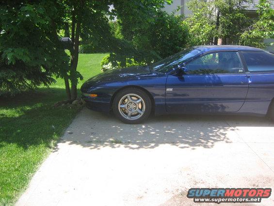 1995 Ford Probe parked on concrete driveway next to grass and trees