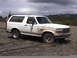 1993 Ford Bronco - White 1993 Ford Bronco parked on a gravel lot under a cloudy sky.