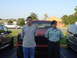 1981 Ford Bronco - Two men pose for a photo in front of a red SUV, with other vehicles in the background.