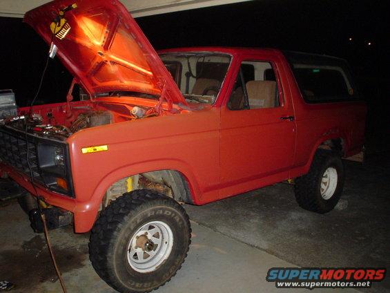 Red SUV with hood up, parked in a garage. Looks like it's being worked on