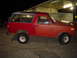1981 Ford Bronco - A red SUV is parked outside a building at night, showing its side profile.