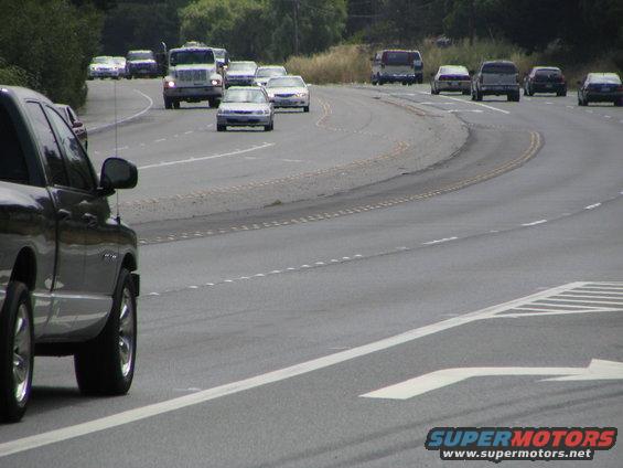 Dark pickup truck side view on a highway with other vehicles