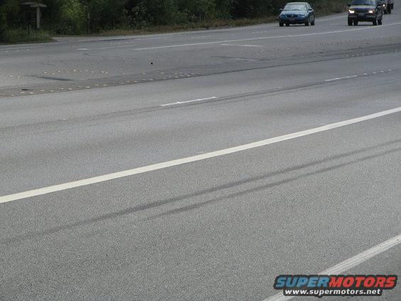 Highway scene with tire marks on the asphalt and two cars driving in the distance