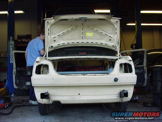 Car with open trunk and doors in a garage, interior visible