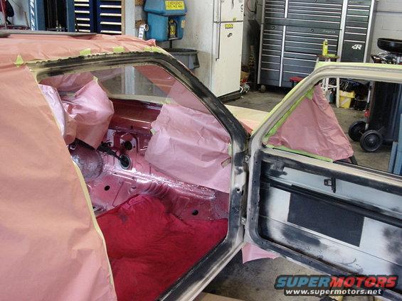 Car interior with doors open, masked for painting. Red carpet visible