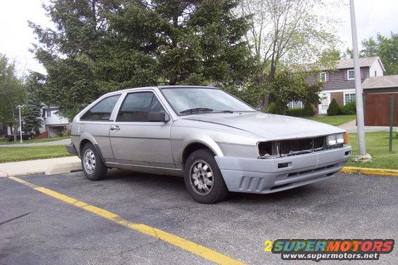 Silver hatchback car with front bumper removed, parked in a lot