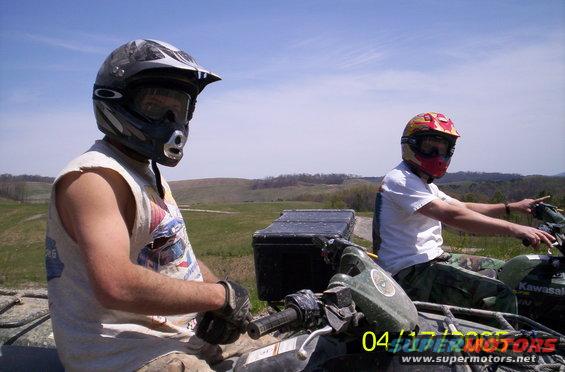 Two people on ATVs in a grassy field