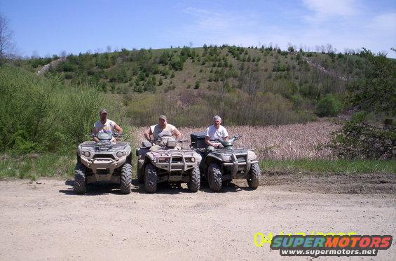 three ATVs parked on a dirt road with riders
