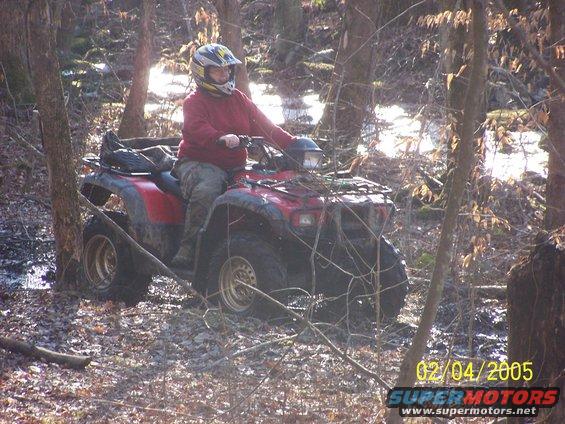 Red 2003 Honda RUBICON ATV with rider in muddy woods