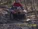 2003 Honda RUBICON - An ATV rider navigates a challenging muddy path through a forest, kicking up water and debris.