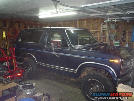 Dark blue SUV with chrome trim and blue pinstripes, hood open, parked in a garage