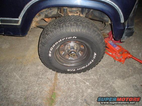 Dark blue vehicle's front wheel and suspension with a red jack underneath