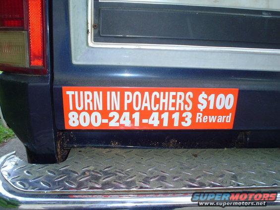 Orange sticker on dark blue vehicle reads 'TURN IN POACHERS $100 800-241-4113 Reward'