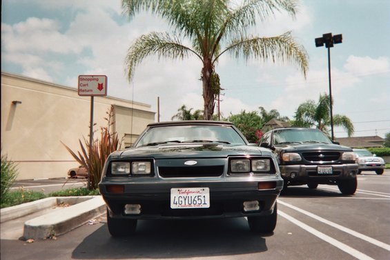Dark grey convertible with a black top, front view, parked in a lot