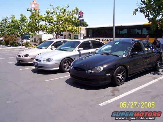 Black Ford Taurus with custom wheels parked in a lot