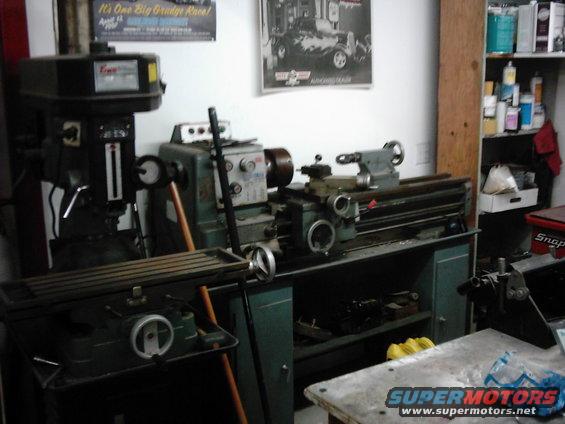 Milling machine and metal lathe in a workshop. Posters on wall, shelves with supplies on right