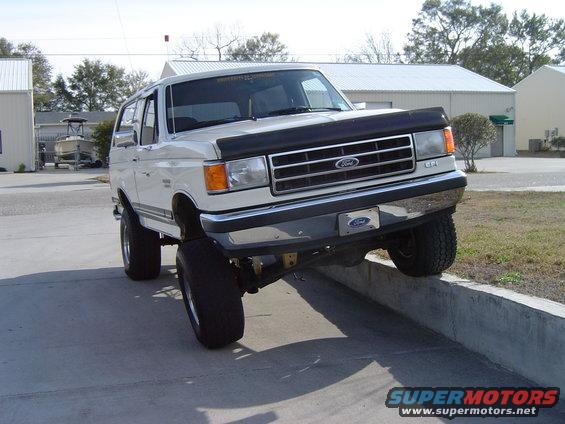 White 1989 Ford Bronco with lifted suspension on a concrete curb