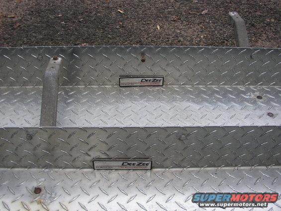 Diamond plate metal with two DeeZee emblems and a Supermotors.net watermark
