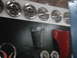1978 Ford Bronco - Various automotive parts, including hubcaps, a grille, and a red fender, are displayed on a wall.