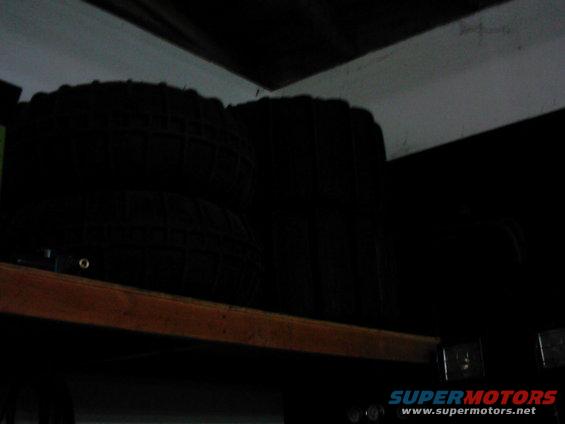Two black tires stacked on a wooden shelf