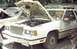 1985 Ford Crown Victoria LTD - Junkyard scene with a white 1985 Ford LTD Crown Victoria, hood up, showing engine bay.