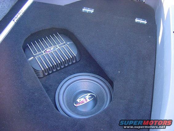 Car trunk with subwoofer and amplifier, text 'RACY' visible on bar