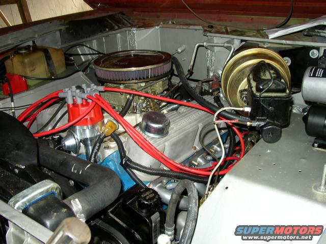 Close-up of a V8 engine bay, showing distributor, carburetor, brake booster, and wiring