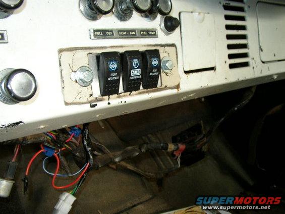White dashboard interior with three black rocker switches labeled 'FRONT AIRLOCKER', 'ARB COMPRESSOR', and 'REAR AIRLOCKER', plus exposed wiring