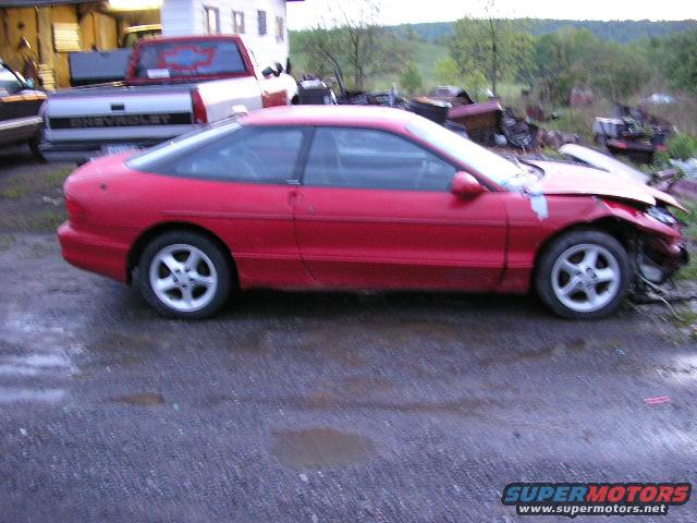 red sports coupe with damaged front end, parked next to a Chevrolet pickup truck