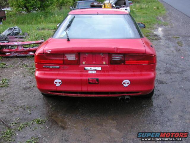 Red 1994 Ford Probe GT rear view, dented trunk lid, skull stickers on bumper