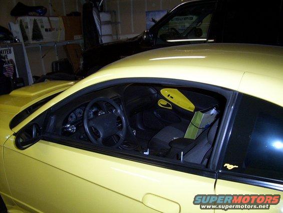 Yellow coupe interior with black dashboard and seats. Another dark vehicle is behind it