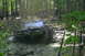 1974 Ford Bronco - A blue 1974 Ford Bronco struggles through deep mud on an off-road trail, with another vehicle visible in the background.