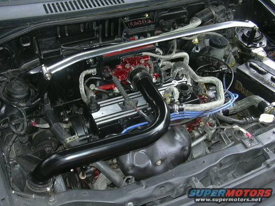 Engine bay with black intake pipe, red accents on engine components, and a silver strut bar