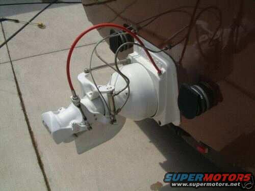 Close-up of a white jet ski pump assembly with a red hose attached, resting on a concrete surface