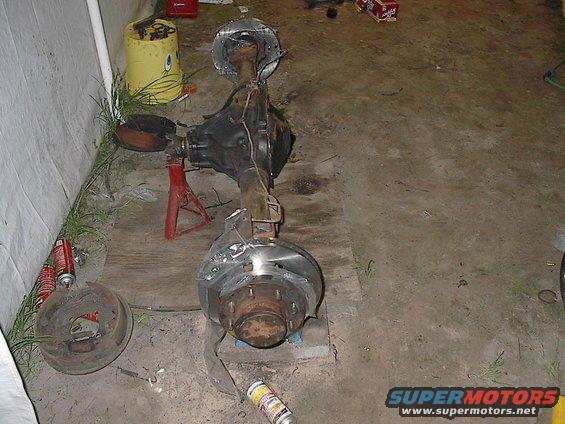 Rear axle assembly on red jack stands, with brake drums and rotors visible