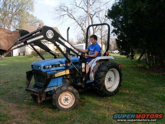 New Holland 1715 tractor with front loader, driven by a young man